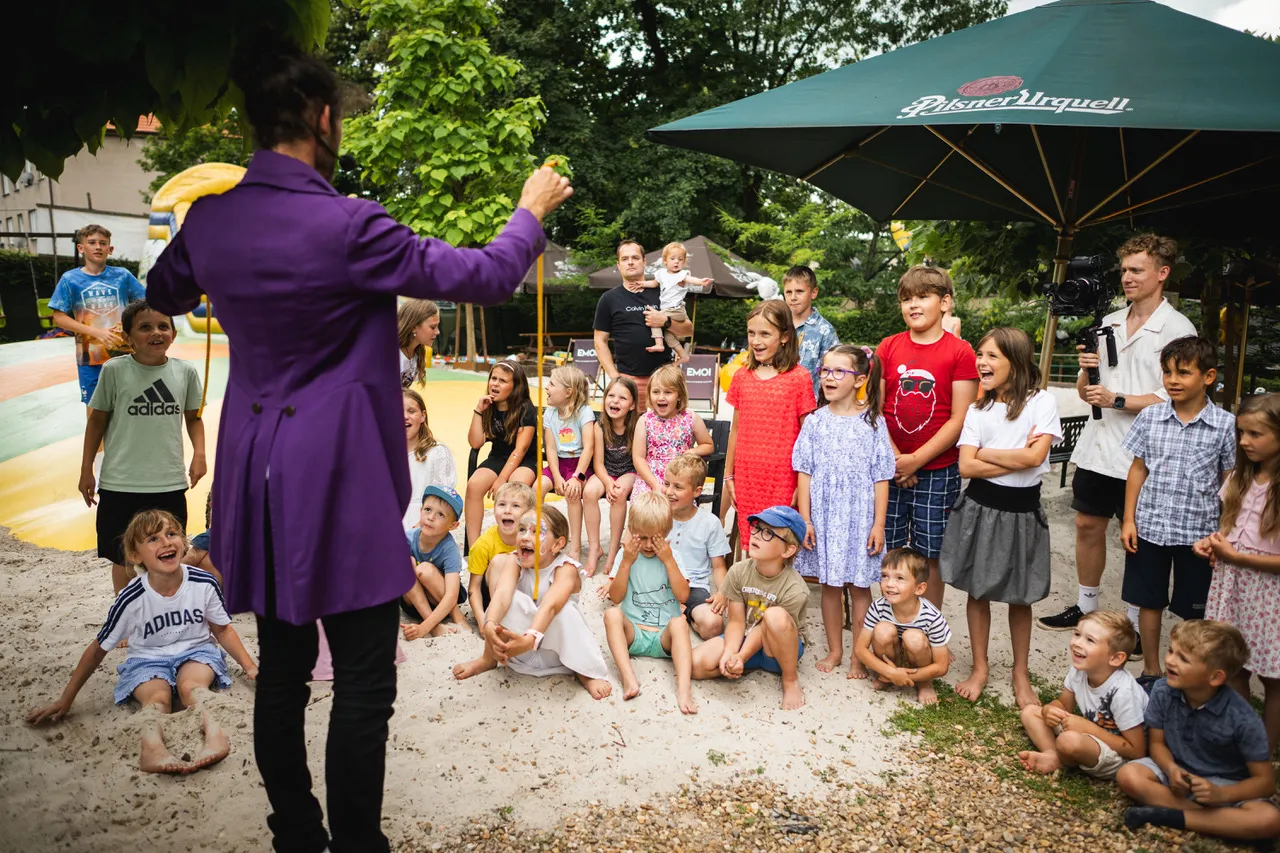 děti sledují kouzelnické vystoupení venku v letním prostředí